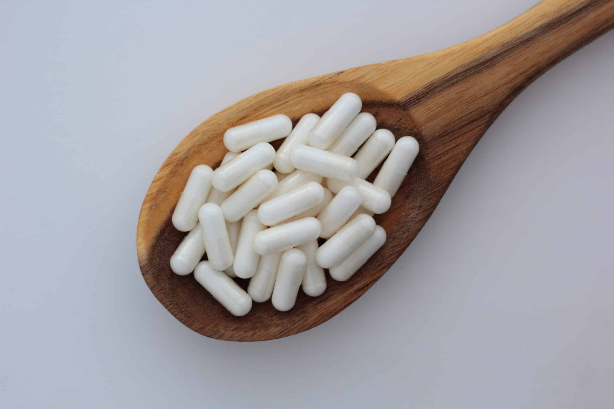 Closeup of myo-inositol capsules on wooden spoon